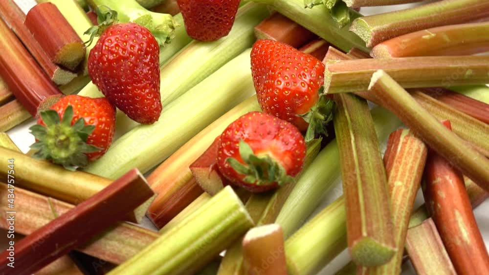 Whole ripe strawberries lie on pieces of rhubarb stalk, products to enhance immunity, background