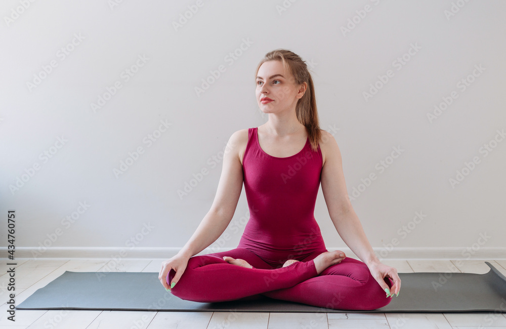 Young healthy beautiful woman practicing yoga at home sitting in lotus pose on yoga mat meditating relaxed. Indoor and outdoor workout. Sport and healthy active lifestyle concept. Young healthy beautiful woman practicing yoga at home sitting in lotus pose on yoga mat meditating relaxed. Indoor and outdoor workout. Sport and healthy active lifestyle concept.
