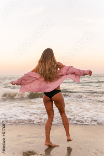 A sports girl runs along the embankment of the sea. A slender girl runs along the beach against the background of the sea. Healthy woman running on the beach