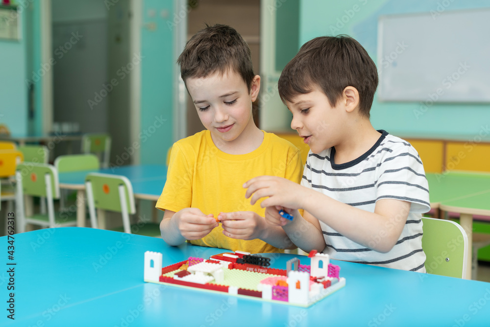 Fototapeta premium two boys are enthusiastically playing blocks in the kindergarten. Leisure in kindergarten