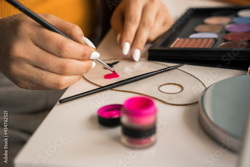 Woman blending liquid pink eyeshadows on the palette while preparing creative makeup
