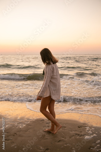 A slender girl in white clothes runs along the beach against the background of the sea. A sports girl runs along the embankment of the sea. Healthy woman on the beach