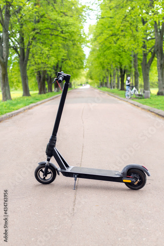 Electric scooter in the park. Cruising among the green trees on a road. Modern eco-transport. Concern for the environment.