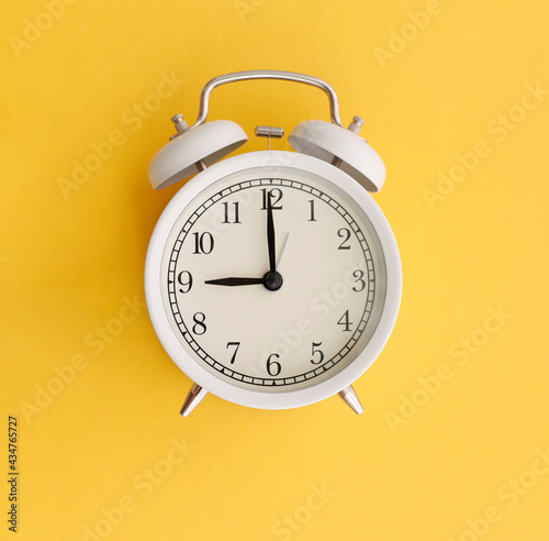 white table clock on yellow and pink background time