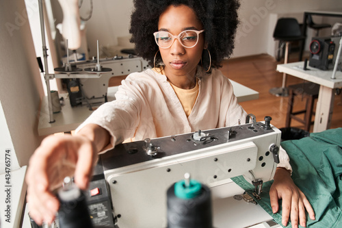 Multiracial woman sewing on an industrial re sewing clothes machine