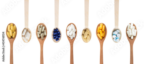 Top view Variety of vitamin and mineral pills in wooden spoon isolated on white background