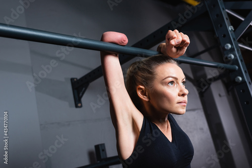 Obraz na płótnie sportswoman with amputated forearm working out on horizontal bar