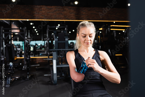 sportive woman with amputated forearm opening sports bottle in gym