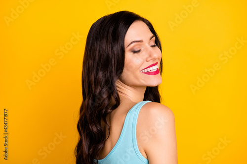 Photo of tender inspired lady close eyes shiny beaming smile wear blue top isolated yellow color background