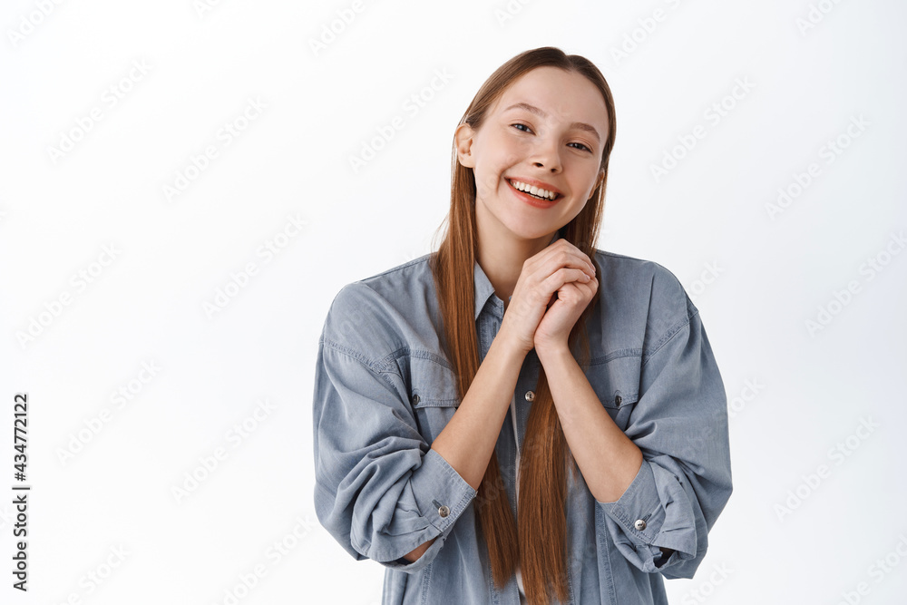 Cute and romantic girl, hands together, smiling and look admiration and love at camera, being grateful, thanking you, receive praises or compliments, being flattered, standing over white background Cute and romantic girl, hands together, smiling and look admiration and love at camera, being grateful, thanking you, receive praises or compliments, being flattered, standing over white background