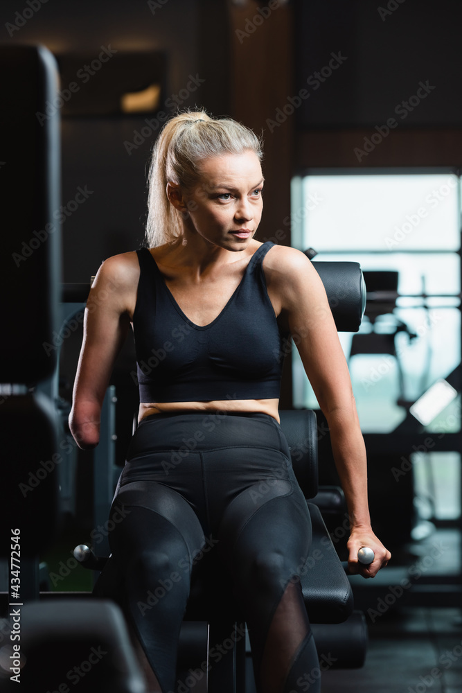 amputee woman in black sportswear working out on fitness machine amputee woman in black sportswear working out on fitness machine