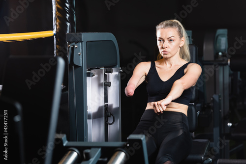 sportswoman with amputated forearm doing abs exercise on fitness machine