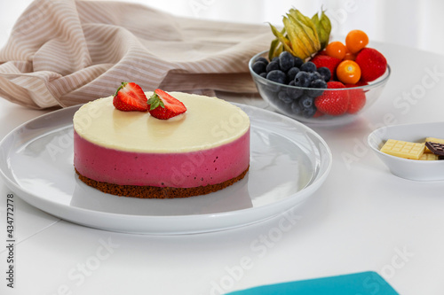 Decoration of vegetarian dessert, cake with berries. Ingredients: almond sponge biscuit, raspberry mousse, white chocolate ganache. The concept of vegan treats.