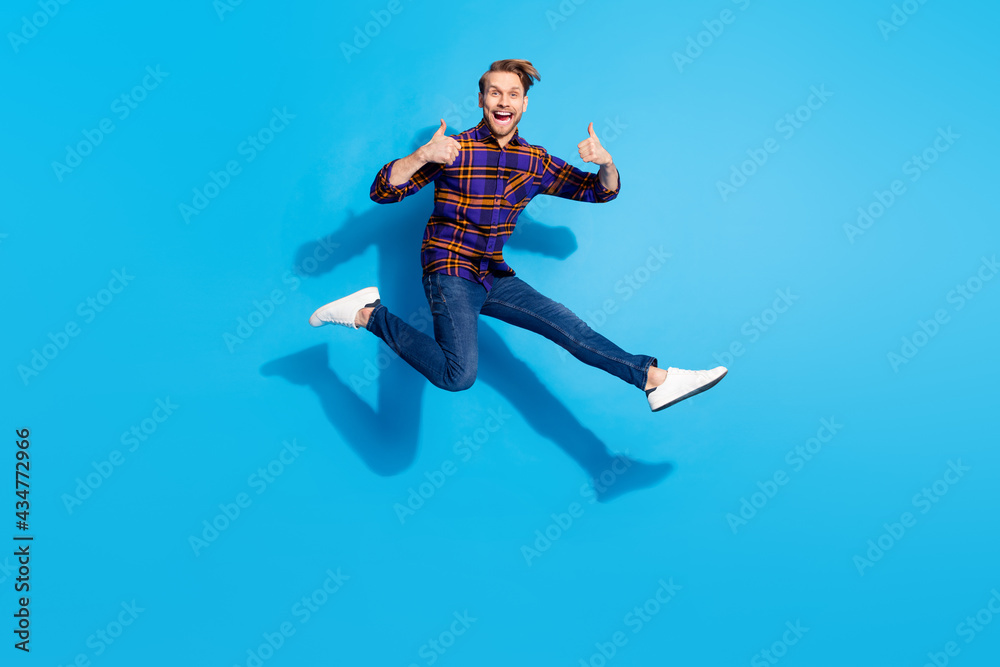 Full length portrait of excited crazy guy show two thumbs up toothy smile rush isolated on blue color background