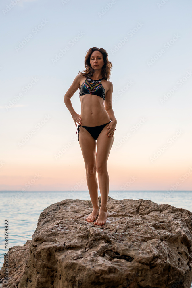 Young woman in a swimsuit posing on the rocks. Young woman in a swimsuit posing on the rocks.