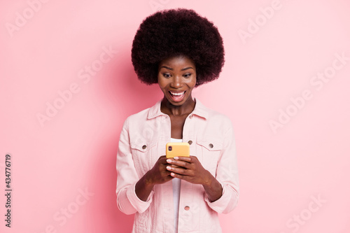 Portrait of pretty amazed cheerful wavy-haired girl using device app 5g fast speed isolated over pink pastel color background
