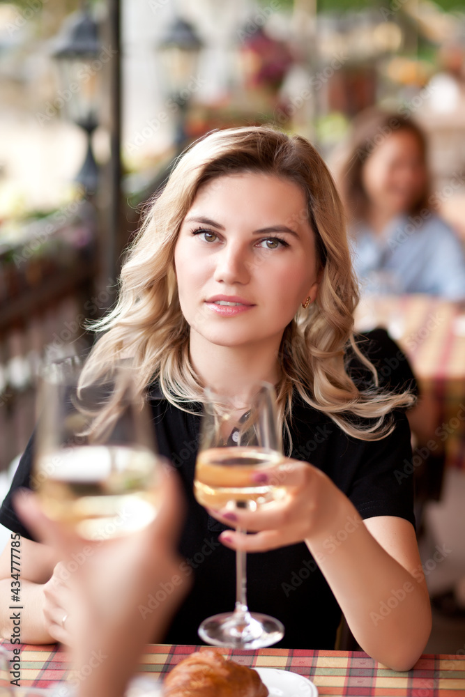 Young woman drinking a white wine in a cafe terrace with friends Young woman drinking a white wine in a cafe terrace with friends