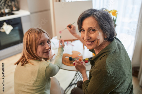 Girl looking to the camera with her granny while creating masterpiece