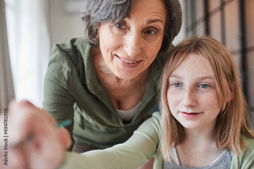Happy child holding brush and painting while her granny helping to her Happy child holding brush and painting while her granny helping to her