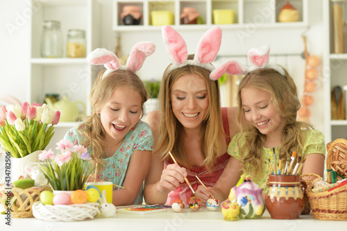  Mother with daughters wearing rabbit ears decorating  Easter eggs