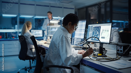 Modern Electronics Research and Development Facility: Beautiful Caucasian Female Engineer Does Computer Motherboard Soldering. Scientists Design Industrial PCB, Silicon Microchips, Semiconductors