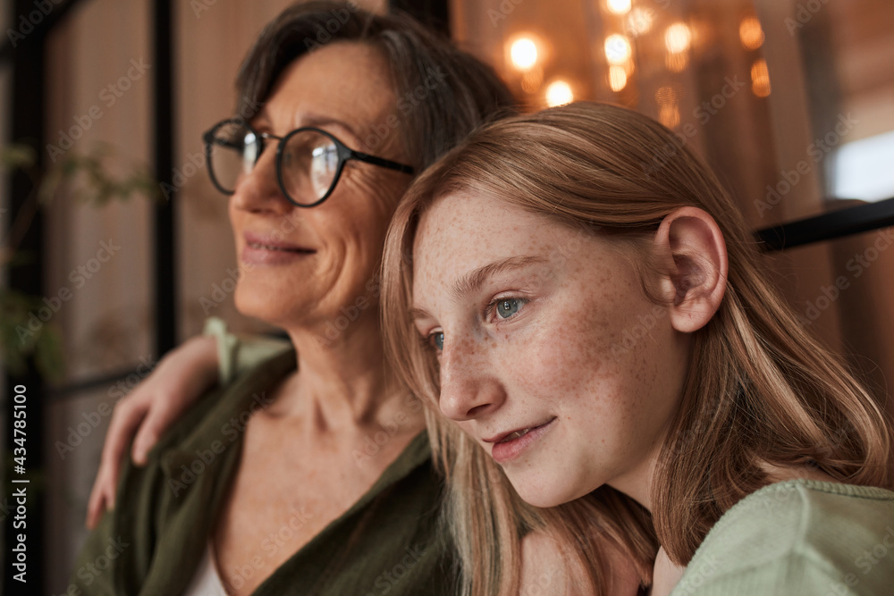 Girl bonding to her senior grandmother and looking away while enjoying Girl bonding to her senior grandmother and looking away while enjoying