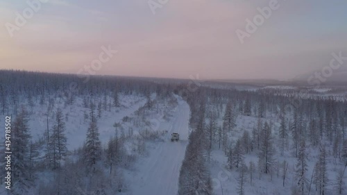 The six-wheel Trekol all-terrain vehicle rides through the snow-covered tundra in the sunset light
 photo