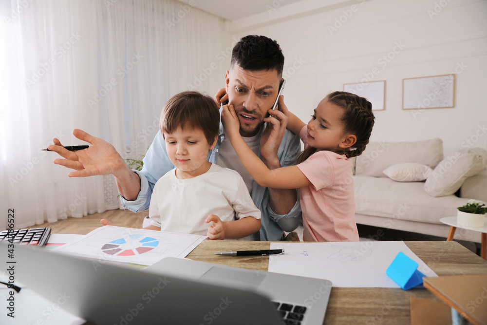 Overwhelmed man combining parenting and work at home Overwhelmed man combining parenting and work at home