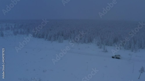 The six-wheel Trekol all-terrain vehicle rides through the snow-covered tundra in the sunset light
 photo