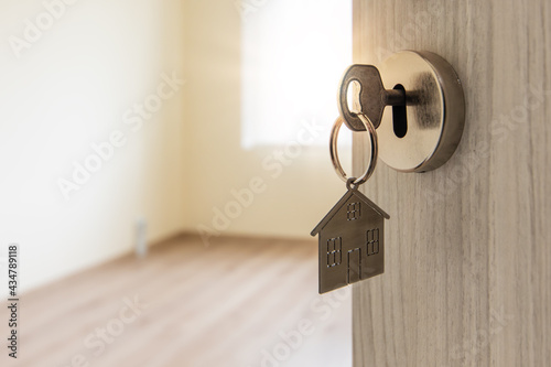 Open door to a new home with key and home shaped keychain. Mortgage, investment, real estate, property and new home concept
