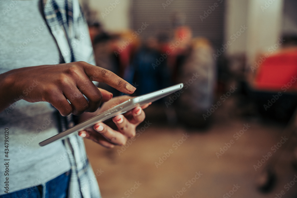Close up mixed race female typing on digital tablet standing in farm store room Close up mixed race female typing on digital tablet standing in farm store room