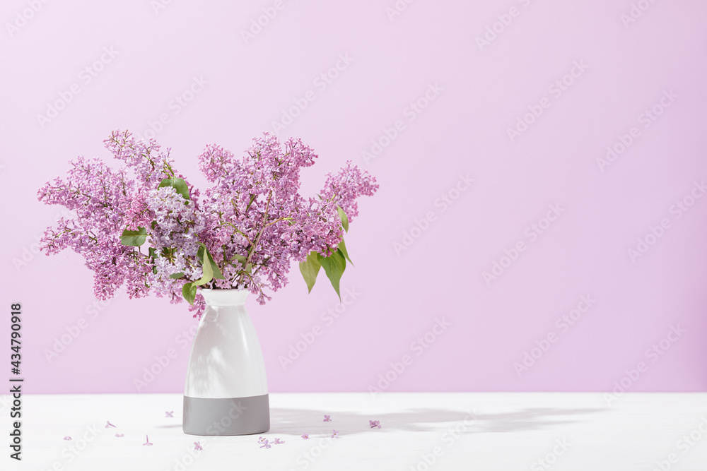 Vase with fresh blooming lilac flowers standing on table Vase with fresh blooming lilac flowers standing on table