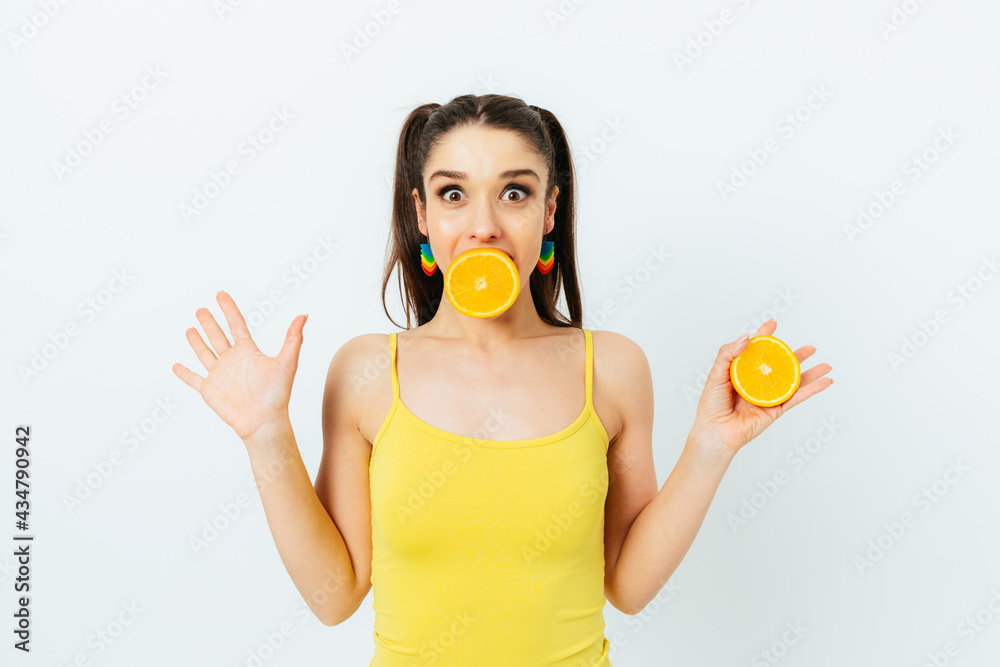 Cheerful playful young woman holding half an orange Cheerful playful young woman holding half an orange