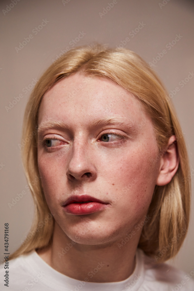 Feminine albino boy with long blonde hair looking away while posing at the studio Feminine albino boy with long blonde hair looking away while posing at the studio
