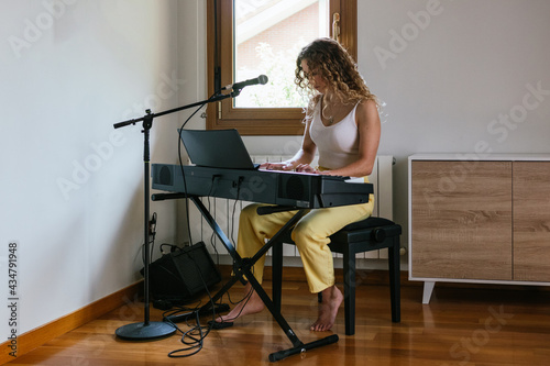 Young woman playing piano at home studio