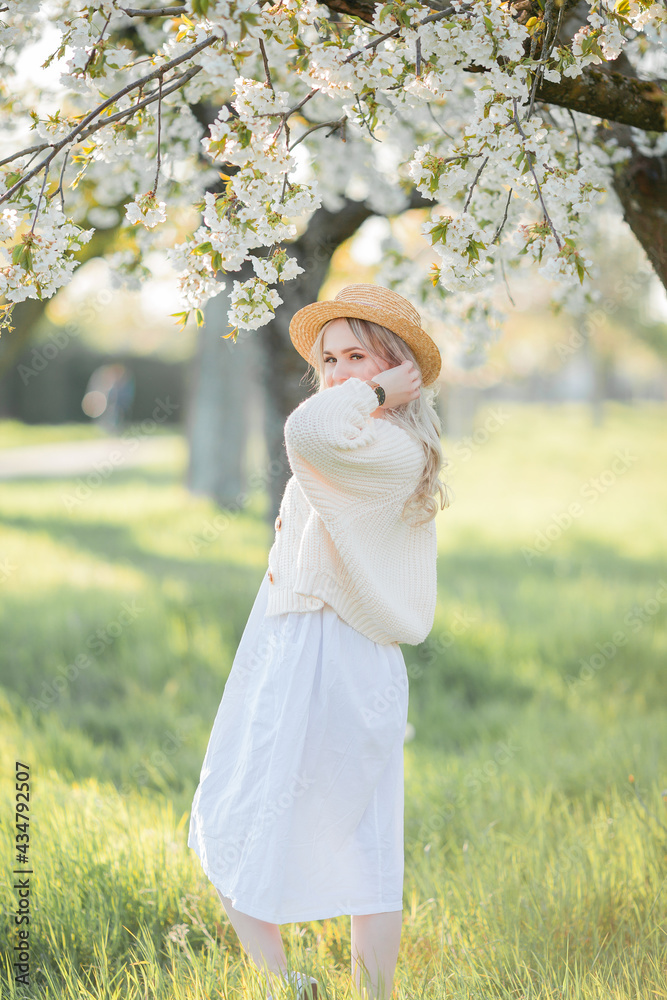Beautiful young woman in a wicker hat is resting on a picnic in a blooming garden. White flowers. Spring. Happiness. Beautiful young woman in a wicker hat is resting on a picnic in a blooming garden. White flowers. Spring. Happiness.