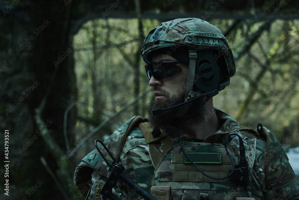 Portrait of airsoft player in professional equipment with machine gun in the forest. Soldier with weapons at war Portrait of airsoft player in professional equipment with machine gun in the forest. Soldier with weapons at war