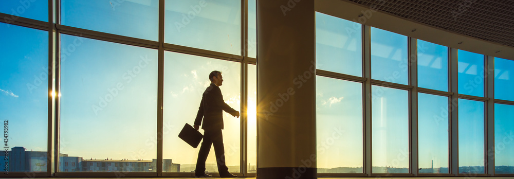 The businessman walk with a suitcase in the office hall
