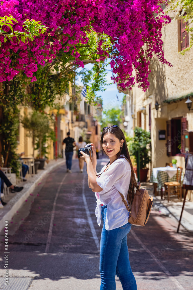 A young tourist woman takes pictures of the beautiful old town Plaka of Athens, Greece
