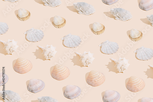 Summer pattern made with different shells, on sand color background. Minimal summer concept.