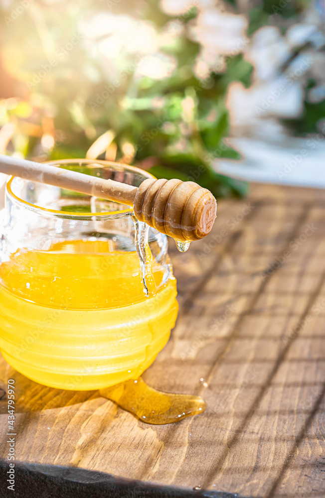 Flowing honey from wooden dipper in a glass jar. Organic honey dipping from the wooden honey spoon. Flowing honey from wooden dipper in a glass jar. Organic honey dipping from the wooden honey spoon.