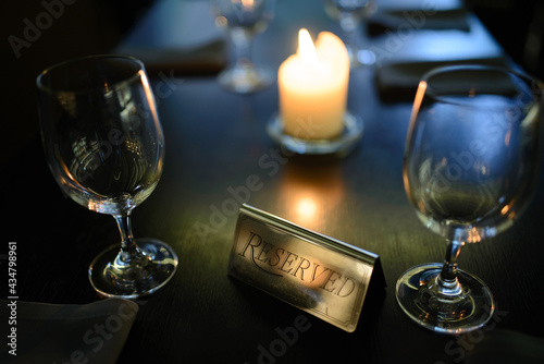 Sign reserved on table with candle burning in background and served table