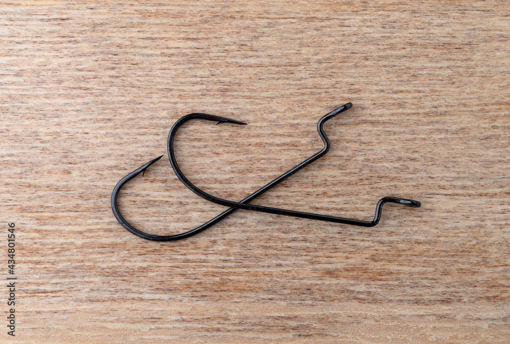 Two offset worm bait hooks on a wood background.