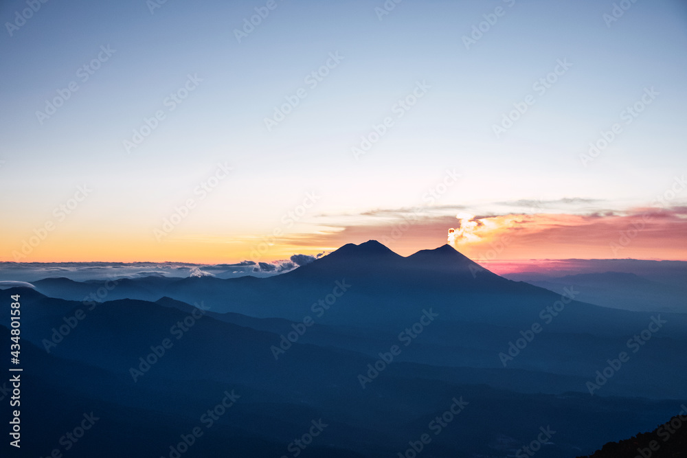 Vista panorámica al Volcán Acatenango el camellón del Volcán de Fuego y una erupción al amanecer