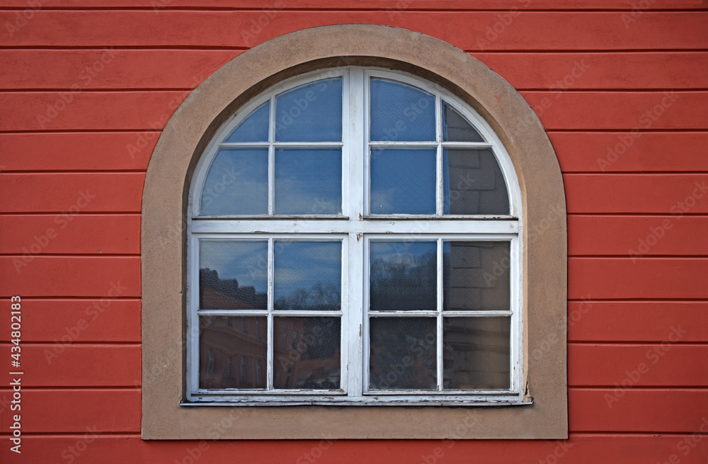 Old wooden window with arch on red wall