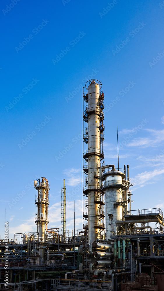 Old methanol distillation refinery column towers and reactors under blue evening sunset sky background at chemical plant. Exterior of silver metal rusty enterprise 16x9 vertical with copyspace.