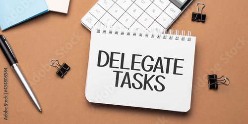 delegate tasks on notepad with pen, glasses and calculator