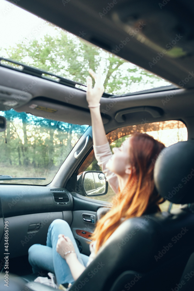 Naklejka premium woman with an open window in the front seat of a car gesturing with her hands interior salon fellow traveler