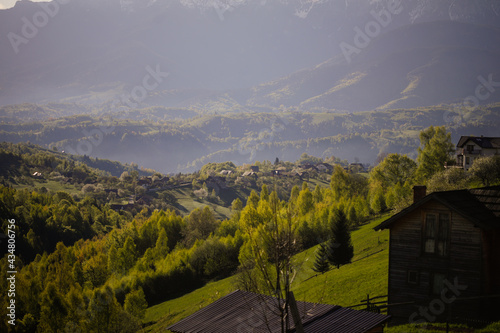 Rolling hills with villages and forests in Transylvania, Romania, with the Bucegi mountains in the background.