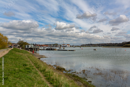 Looking down the River Deben towards the Tide mill in Woodbridge at high tide with a variety of boats moored in the river on a spring day